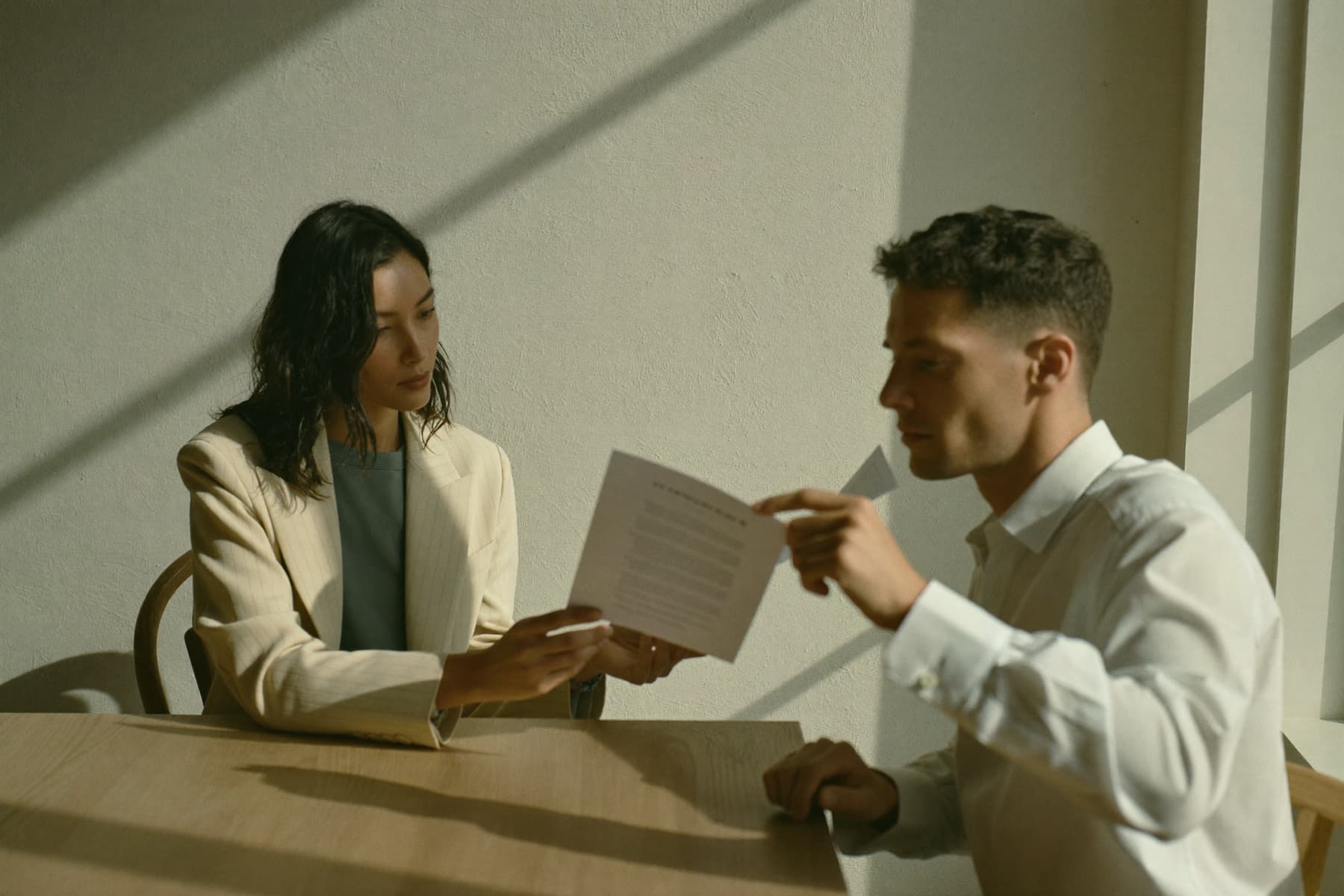 Two professionals reviewing a printed agreement at a table