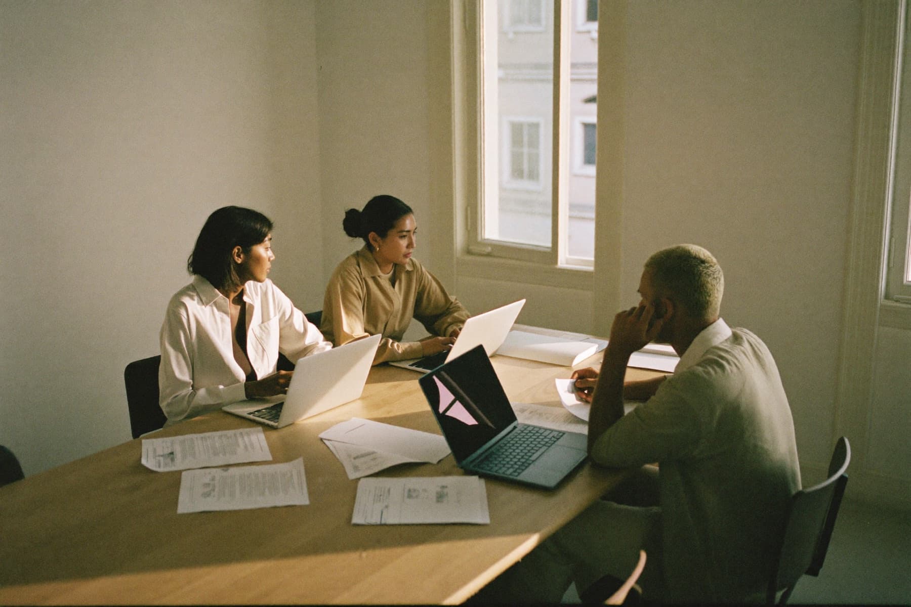 A team working around a table with laptops and printed reports